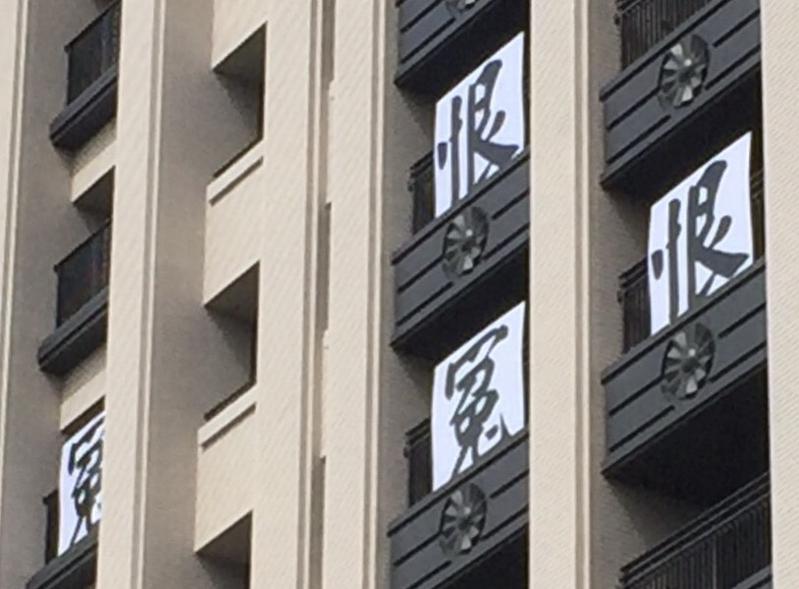 德鑫V1住戶2016年10月在大樓外懸掛標語抗議中國醫藥大學。（圖為「反黑箱護水源設公校自救會」提供）
