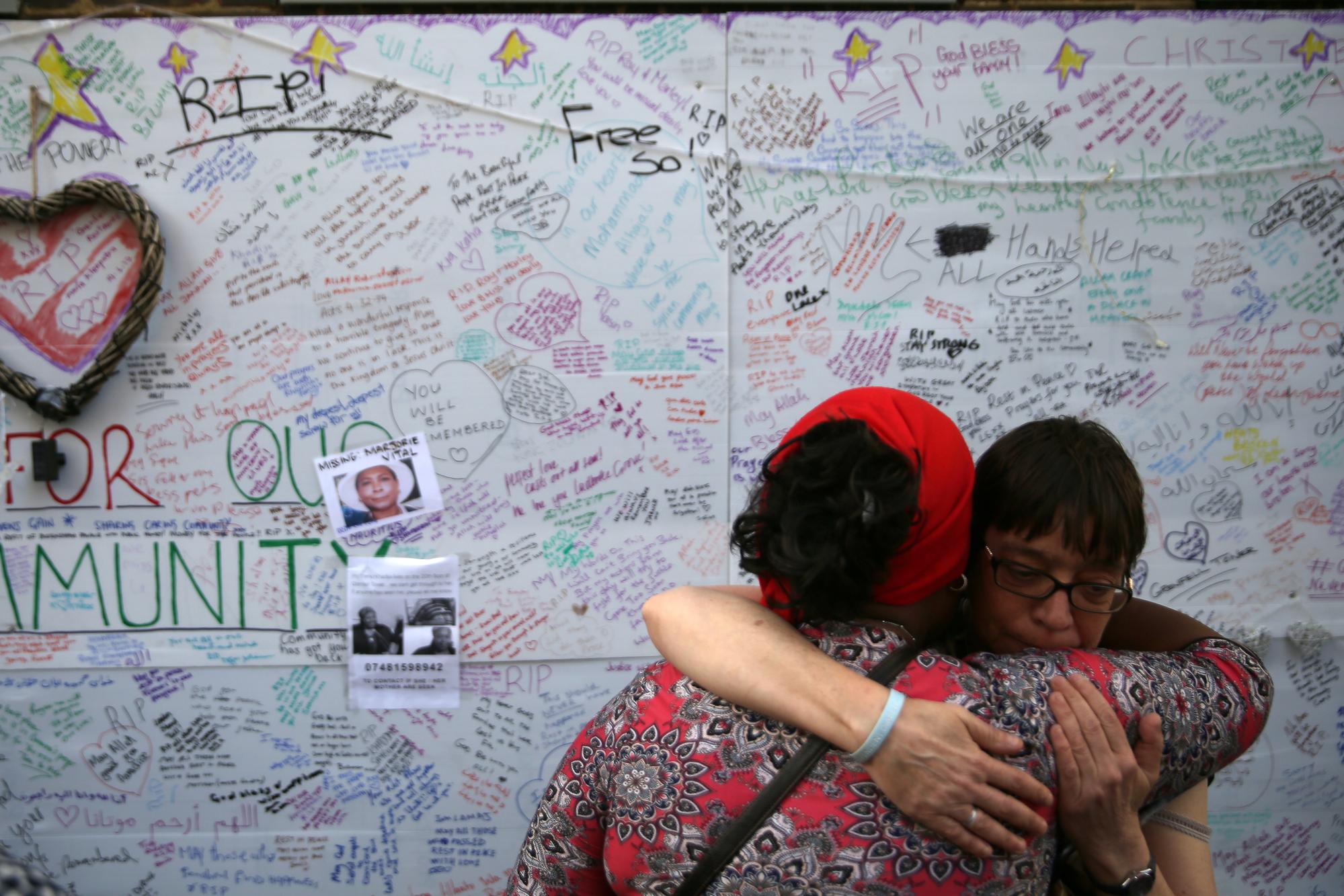 兩位民眾在格蘭菲爾悼念板前相互擁抱。(攝影/AFP PHOTO/Daniel LEAL-OLIVAS)