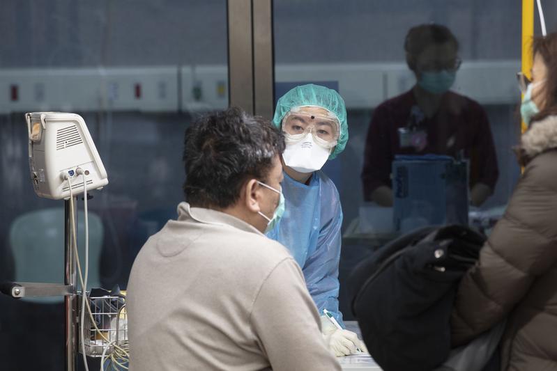 Outside of the Taoyuan General Hospital emergency room, medical workers are conducting preliminary screening for people who have fevers and coughs. (Photo: Yang Tzu-Lei,楊子磊)