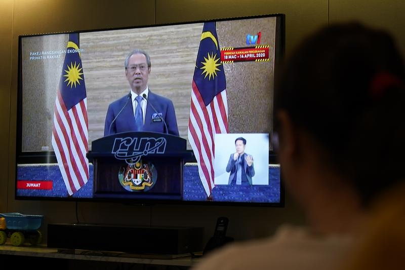 馬來西亞民眾觀看首相慕尤丁（Muhyiddin Yassin）透過電視發布疫情因應政策。（攝影／AP Photo／Vincent Thian／達志影像）