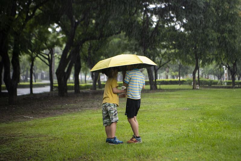 The Runaway Brothers holding up a small yellow umbrella in the rain. Photo by Yang Tzu-lei(楊子磊)