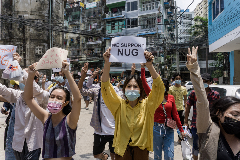 4月27日在仰光街頭，一群反軍事政變的民眾手中舉著支持民族團結政府（NUG）的標語。（攝影／AFP／STR ）
