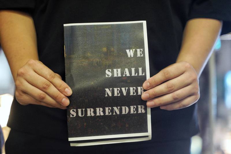 612晚間，嶺南大學學生會成員在旺角派發的傳單：「We Shall Never Surrender」。（攝影／陳朗熹）
