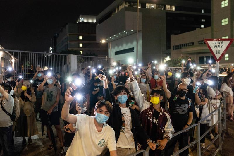 壹傳媒大樓外，人群以手機燈光來送別《蘋果日報》，大樓內員工也以同樣方式呼應人群。（攝影／陳朗熹）