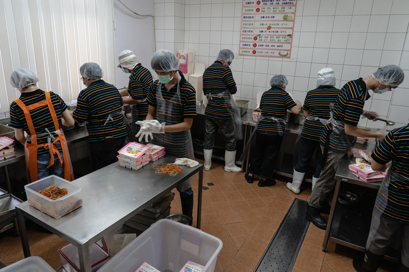 一份營養餐食的背後，不只送餐員，還得由營養師、廚師、配膳員、社工等人共同成就，有許多看不見的成本。圖為弗傳慈心配膳員將個別化的餐點分裝到餐盒內。（攝影／馬雨辰）