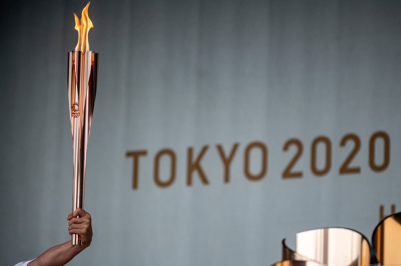 2020東奧是東京二度辦奧運，充滿向1964年首次東奧致意的意味。圖為本次聖火傳遞員高舉2020東京奧運火炬的畫面。（攝影／AFP／Philip Fong）