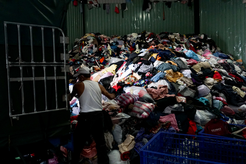 在湯劍雄位在新北市樹林區的舊衣回收場，員工從貨車上卸下從舊衣回收箱的衣物。（攝影／張家瑜）