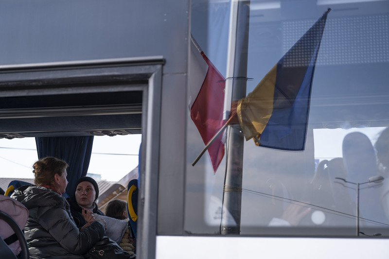 2022年3月15日中午，一輛接送難民的巴士正要從波烏邊境的梅迪卡（Medyka）啟程時，車窗上倒映著波蘭與烏克蘭的國旗。（攝影／楊子磊）