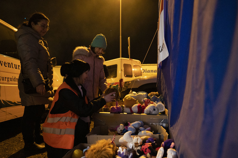 在波蘭東部接近烏克蘭邊界的公路旁，來自世界各地的志工準備了各種物資與食物，讓方才抵達的烏克蘭家庭能夠在此歇息。3月13日晚間，一位烏克蘭女孩在志工的協助下挑選自己喜歡的布偶。（攝影／楊子磊）