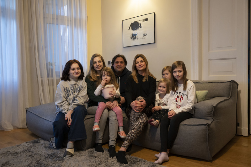 法比安（Monika Fabjan，右4）與來自烏克蘭的漢娜（Hanna，左2）兩家人在法比安住家的客廳裡合影。戰爭爆發後，許多波蘭家庭決定打開家門接待逃難的烏克蘭家庭。（攝影／楊子磊）