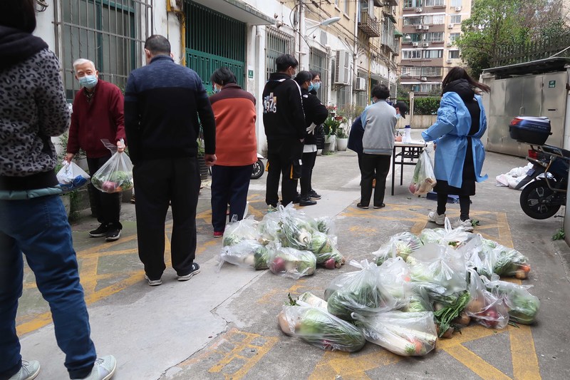 3月31日，上海一處封鎖的小區居民排隊領取蔬菜等食物。（攝影／VCG via Getty Images／VCG）