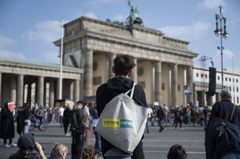 2022年3月25日，一位民眾站在柏林布蘭登堡門前，手提袋上貼著反戰標語：阻止普丁、停止戰爭。（攝影／楊子磊）