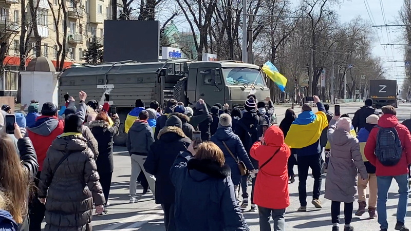 3月20日，赫爾松的民眾手持標語與國旗，走向一輛俄羅斯軍車抗議。（影像／REUTERS／達志影像）