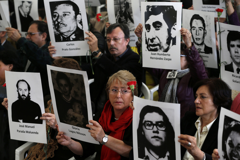 2013年9月10日，時為智利總統候選人的巴舍萊（中）在格里馬爾迪集中營的軍事政變40週年紀念儀式上，舉起政治受難者的照片。（攝影／REUTERS／Ivan Alvarado／達志影像）