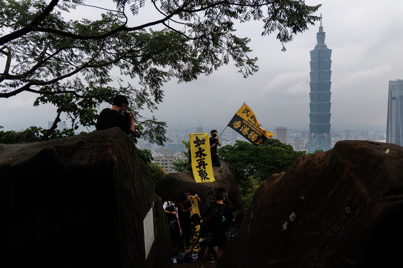 許多在台港人和支持者，在「兄弟爬山 繼續努力」612香港行動遊行前，登上象山六巨石舉起標語。（攝影／鄭宇辰）