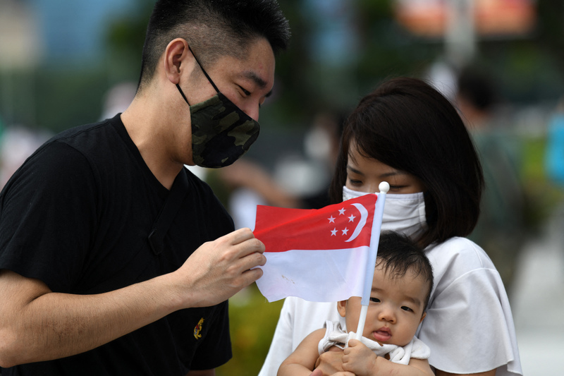 2020年8月9日,一對夫婦與他們的孩子在魚尾獅公園參加新加坡國慶慶祝活動。(攝影/AFP/Roslan Rahman)