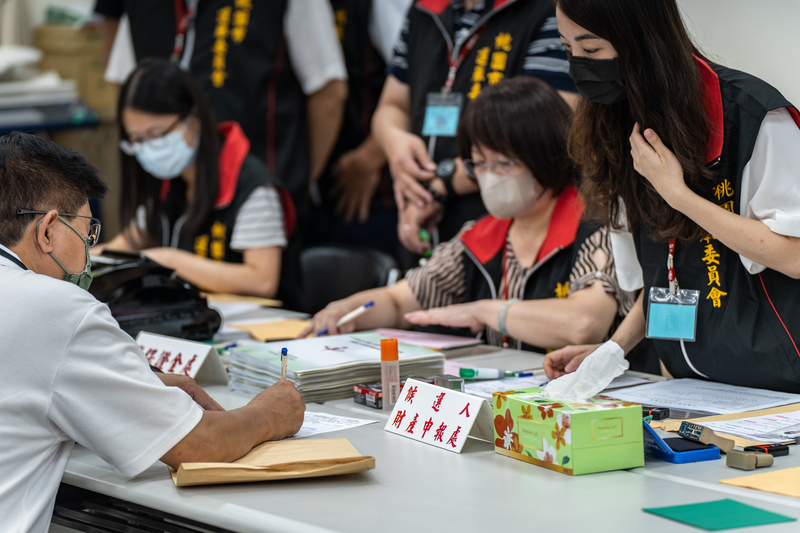 修法後，今年議員候選人財產申報成為必要條件，要確實填寫才能登記參選。圖為桃園市選委會工作人員正在檢核登記參選議員的候選人財產申報資料。（攝影／陳曉威）