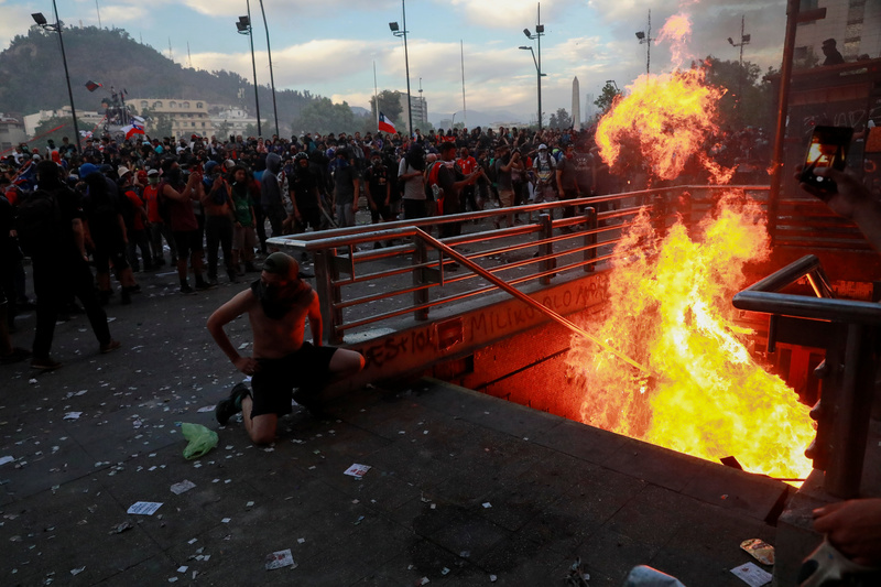 2019年10月25日，在智利聖地牙哥的示威活動中，群眾聚集在被燃燒路障堵塞的地鐵入口前。（攝影／REUTERS／Henry Romero／達志影像)