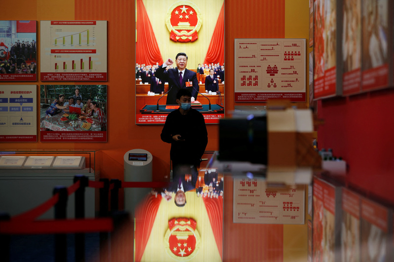 2022年10月12日，在中國共產黨第二十次全國代表大會前夕，一位民眾走過「奮進新時代」展場裡習近平宣誓的照片。（攝影／REUTERS／Florence Lo／達志影像）