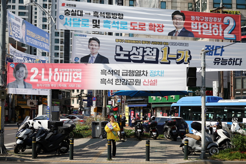 2022年5月31日，韓國正義黨的比例代表制市議員候選人，同時也是一位大學生的盧珍瑞（Noh Seo-jin音譯），站在首爾街頭的競選布條下。（攝影／REUTERS／Kim Hong-Ji／達志影像）