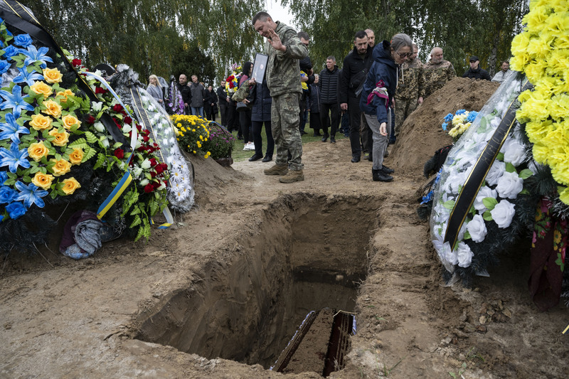 親友們輪流朝在國土防衛隊隊員波比哈（Oleksiy Pobihai）的靈柩撒下一把土，其中一位在轉身離去前向靈柩揮手道別。（攝影／楊子磊）