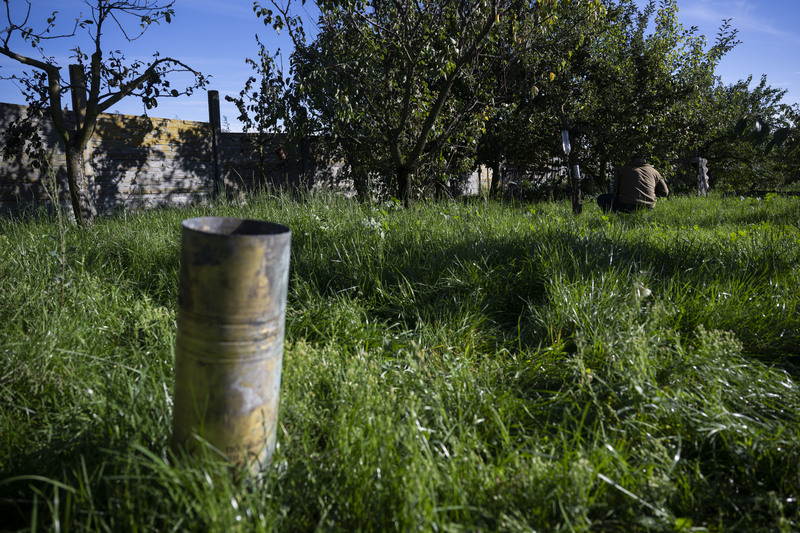庭院裡整理果樹的人，身後有俄軍的重兵器留下的彈殼。（攝影／楊子磊）