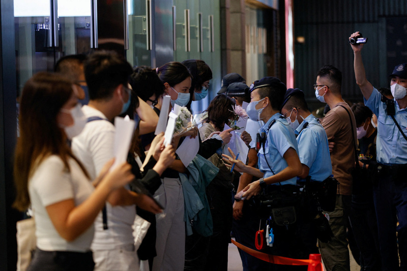 11月28日，在香港中環，人們拿著白紙上街舉行烏魯木齊火災遇難者紀念活動期間，警察前往檢查他們的身分證件。（攝影／REUTERS／Tyrone Siu）