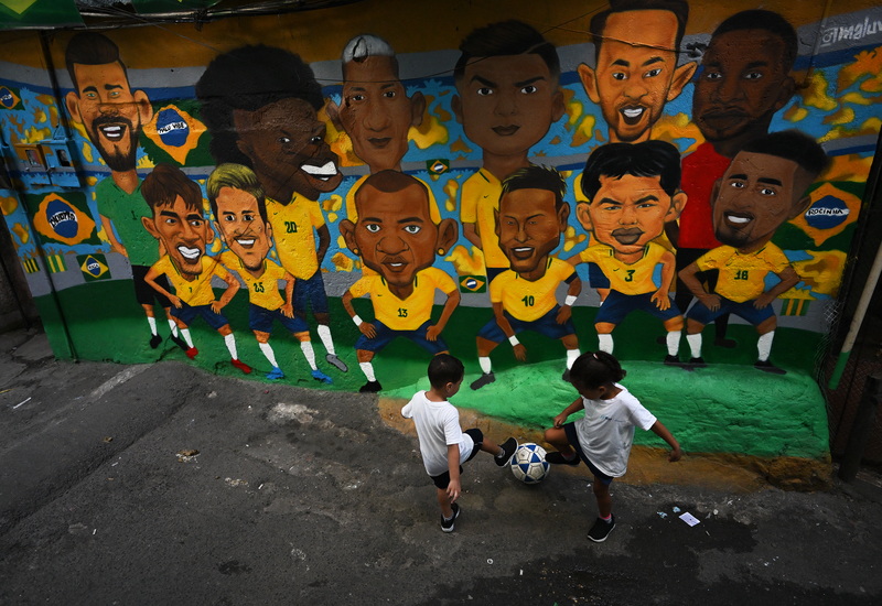 2022年11月23日，巴西里約熱內盧的Rocinha貧民窟裡，孩子們在巴西國家足球隊的壁畫前踢球。（攝影／AFP／Carl de Souza）