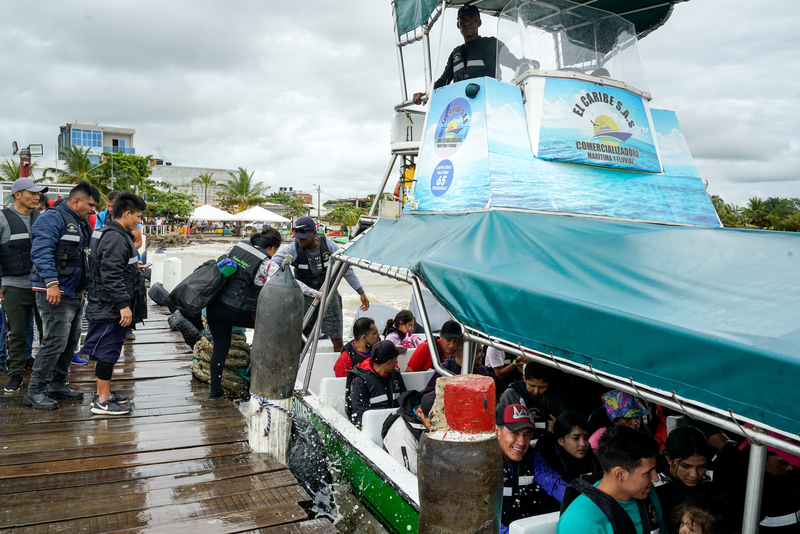 People from Latin America, Asia and Africa board a boat in Necoclí, Columbia, with tents, rain boots and sleeping bags as they make their way to the Darién Gap, Nov. 4, 2022. (Credit: Chen Yingyu)