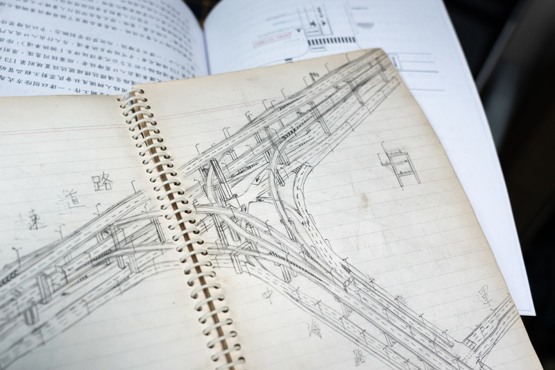 莊哲維20年前念國中時就開始畫馬路，這本屏東東港國中的「傳家寶」筆記本裡有各種手繪道路平面、立體圖。（攝影／陳曉威）