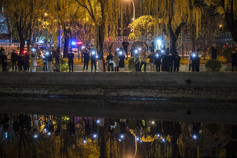 2022年11月27日，示威者在北京亮馬河邊舉起手機燈光，反對言論審查制度和中國疫情封控措施。（攝影／Getty Images／Kevin Frayer）