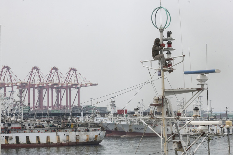 針對我國遠洋漁業中的外籍漁工勞動條件惡劣，美國勞動部兩度將台灣漁獲列入「童工及強迫勞動製品清單」。圖為2020年12月，一名外籍漁工在前鎮漁港內停泊的漁船上粉刷油漆。（攝影／楊子磊）