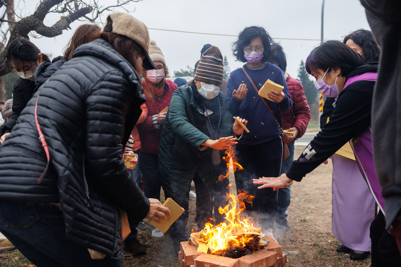 民眾焚燒金紙，伸手感受火煙籠罩全身、虔誠祈福。（攝影／鄭宇辰）