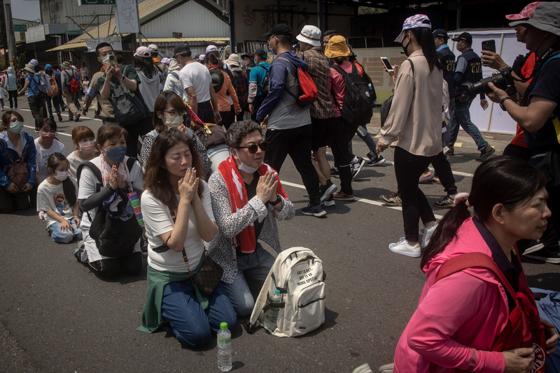 2023年4月23日，大甲媽祖繞境隊伍抵達彰化，等待鑽轎腳的民眾跪坐在神轎即將經過的道路上。（攝影／Getty Images／Chris McGrath）