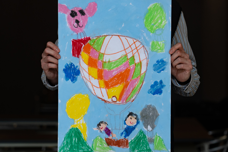 佑佑爸爸拿著孩子的畫，畫中的熱氣球載著大人小孩開心升空。（攝影／陳曉威）