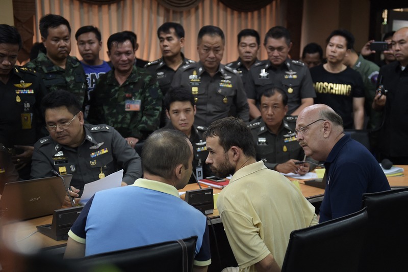 為刑事罪被告提供口譯協助是人權保障的一環。圖為2015年9月4日，在泰國曼谷大都會警察局，被政府認定為曼谷四面佛爆炸案嫌疑人的維吾爾族男子Adem Karadag（中）在接受調查時與口譯人員（左）交談。（攝影／AFP／Christophe Archambault）