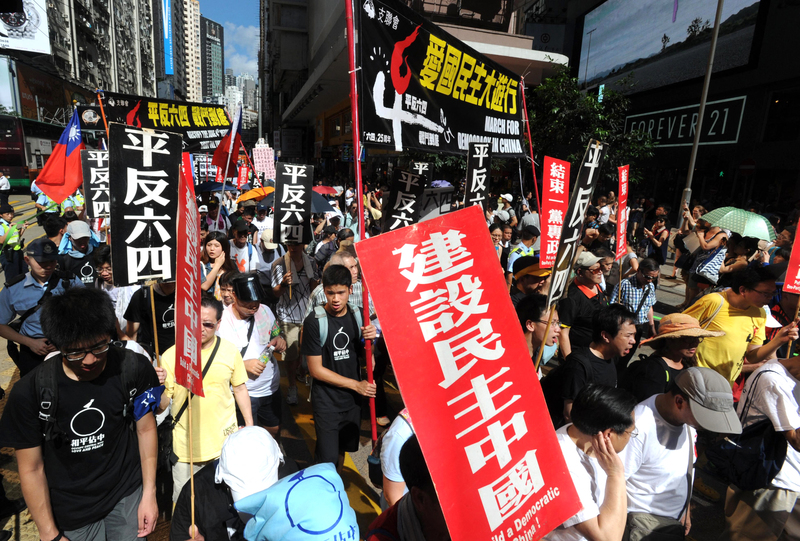2014年6月1日，香港市民支援愛國民主運動聯合會（簡稱支聯會）舉辦「愛國民主大遊行」，民眾手持「平反六四」、「結束一黨專政」、「建設民主中國」等標語上街。當時，「讓愛與和平佔領中環」運動正起。（攝影／The Yomiuri Shimbun via AFP／Mitsuru Tamura）