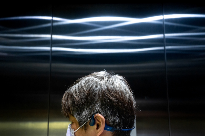楊聖弘配戴骨傳導耳機，在台北捷運工作人員協助下搭乘車站電梯。（攝影／陳曉威）