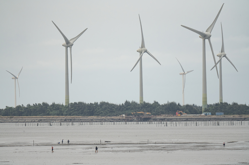 在太陽光電施工前的線西水道，撿拾紫雲蛤的人與崙尾陸域風機。（攝影／許震唐）