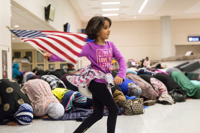 2017年1月29日，美國穆斯林在達拉斯沃斯堡國際場抗議川普頒布穆斯林國家旅行禁令，一名女孩在禮拜期間揮舞美國國旗。（攝影／REUTERS／Laura Buckman）