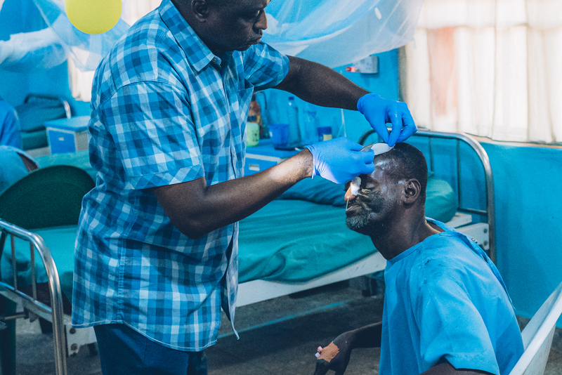 整形外科醫生穆巴亞（Kefas Mbaya）在索科托的壞疽性口炎醫院術後恢復病房，為45歲的倖存者阿瑪杜（Amadu）更換繃帶。（攝影／Fabrice Caterini／Inediz）