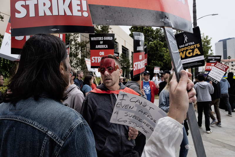 2023年5月24日，在加州伯班克的華納兄弟工作室外，罷工糾察隊舉著標語在工作室入口附近行走。（攝影／AP Photo／Richard Vogel／達志影像） 

