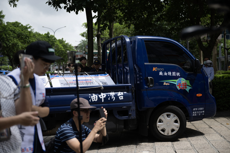 8月1日上午，台灣勞動派遣產業工會舉行記者會期間，一輛寫著桃園煉油廠的貨車從工會成員旁開進中油廣場，車上載著兩面說明板，分別為「中油公司人員進用途徑」與「中油桃園煉油廠公務車駕駛員陳情案件說明」。（攝影／楊子磊）