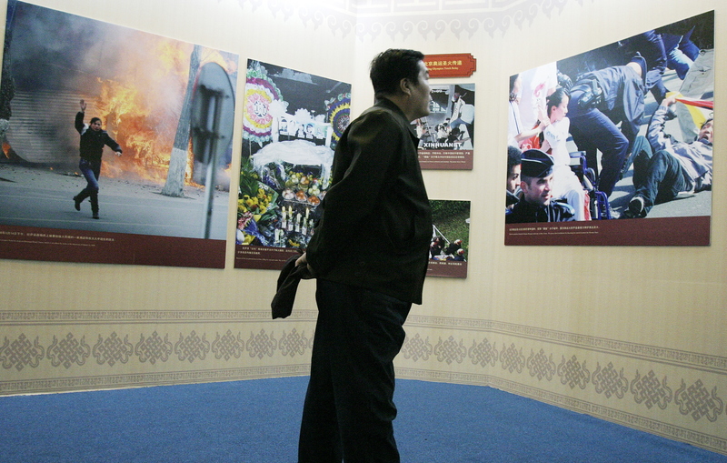 2009年2月26日，在北京民族文化宮，一名中國遊客在「西藏民主改革50週年展」上觀看西藏314事件的官方觀點照片。（攝影／ACOREANO ORIENTAL／China Xtra via AFP）