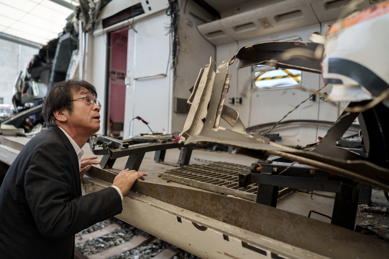 安部誠治前往查看台鐵保存於富岡機廠的太魯閣事故列車，仔細觀察車廂受損的狀況。（攝影／黃世澤）