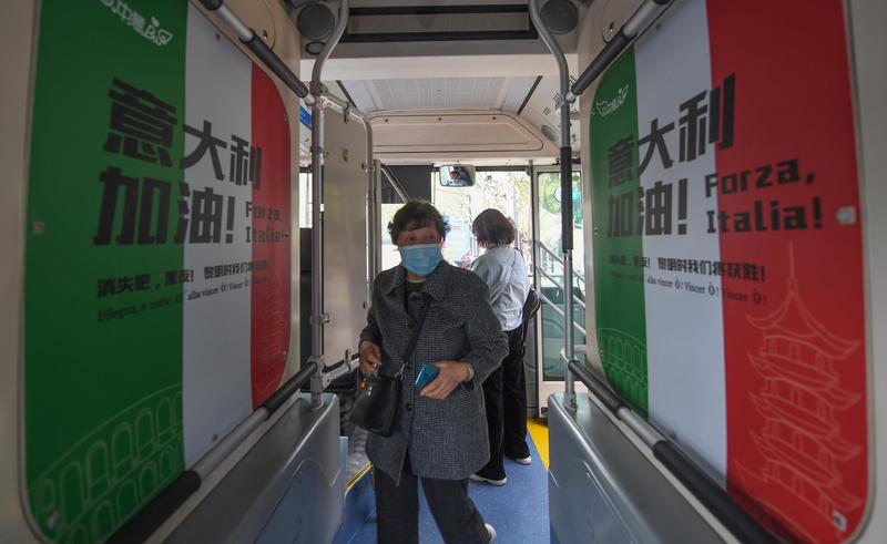 2020年3月26日，在中國浙江省杭州市，戴口罩的乘客登上一輛裝飾著支持義大利抗疫標語的巴士。當時，義大利北部繼中國武漢之後，成為全球COVID-19疫情的震央（epicenter）。（攝影／China News Service via Getty Images／Wang Gang)
