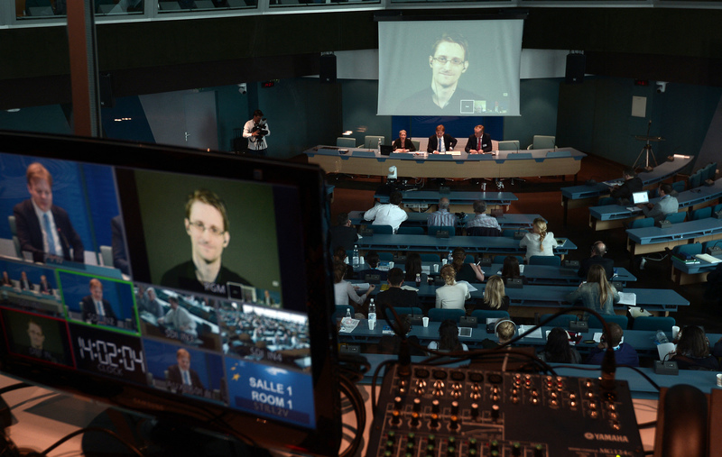 2015年6月23日，愛德華・史諾登（ Edward Snowden）透過來自俄羅斯的視訊連線（圖片上和左下）參加了歐洲議會司法及公民自由委員會的聽證會。當時史諾登因揭露美國國家安全局間諜計畫而被華府稱為駭客和叛徒，而後接受俄羅斯庇護。（攝影／AFP／FREDERICK FLORIN）