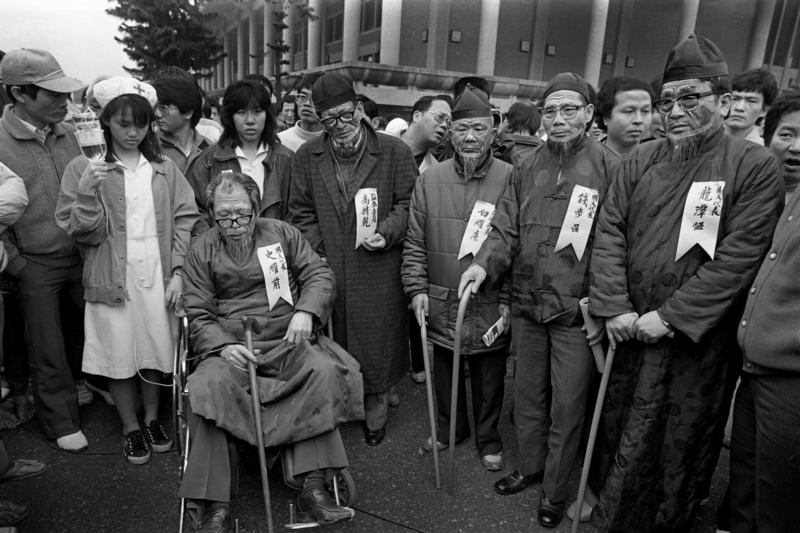 【1988.03.20  國會全面改選活動】為抗議當時的萬年國會，民眾裝扮成只會表決時舉手的資深國代與立委，並主張「國會全面改選」的訴求。（攝影／謝三泰）