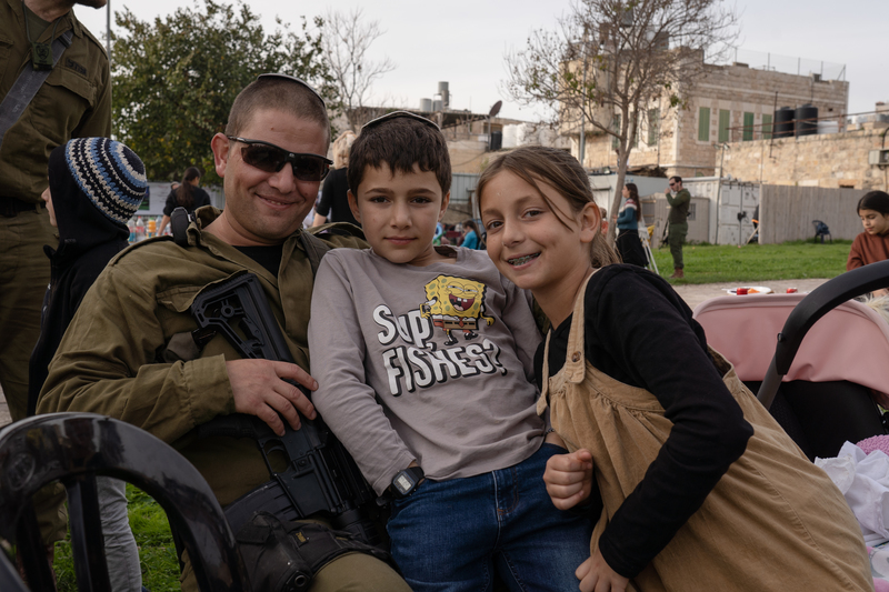 38歲的以色列人舒吉（Shuki Gilbao）與他的子女在希伯崙市中心屯墾區草地上野餐。（攝影／陳彥婷）