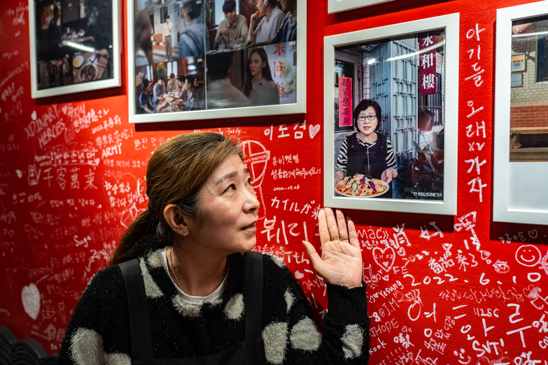 「永和樓」的老闆娘蕭菁運指著牆上的照片，照片裡是在韓國經營第一代永和樓的媽媽。（攝影／陳曉威）